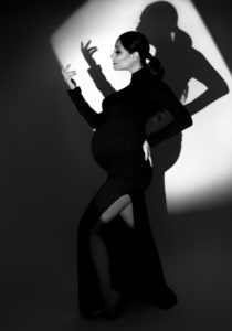 Fashion style maternity photograph of a woman in a black dress