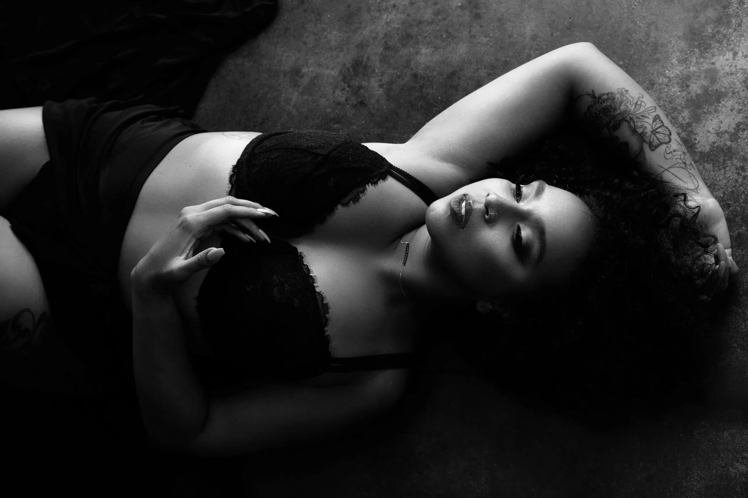 Black and white portrait of a woman in lingerie lying on the ground in a dance like position. Boudoir portrait by Andrea Liora Studios in San Francisco.