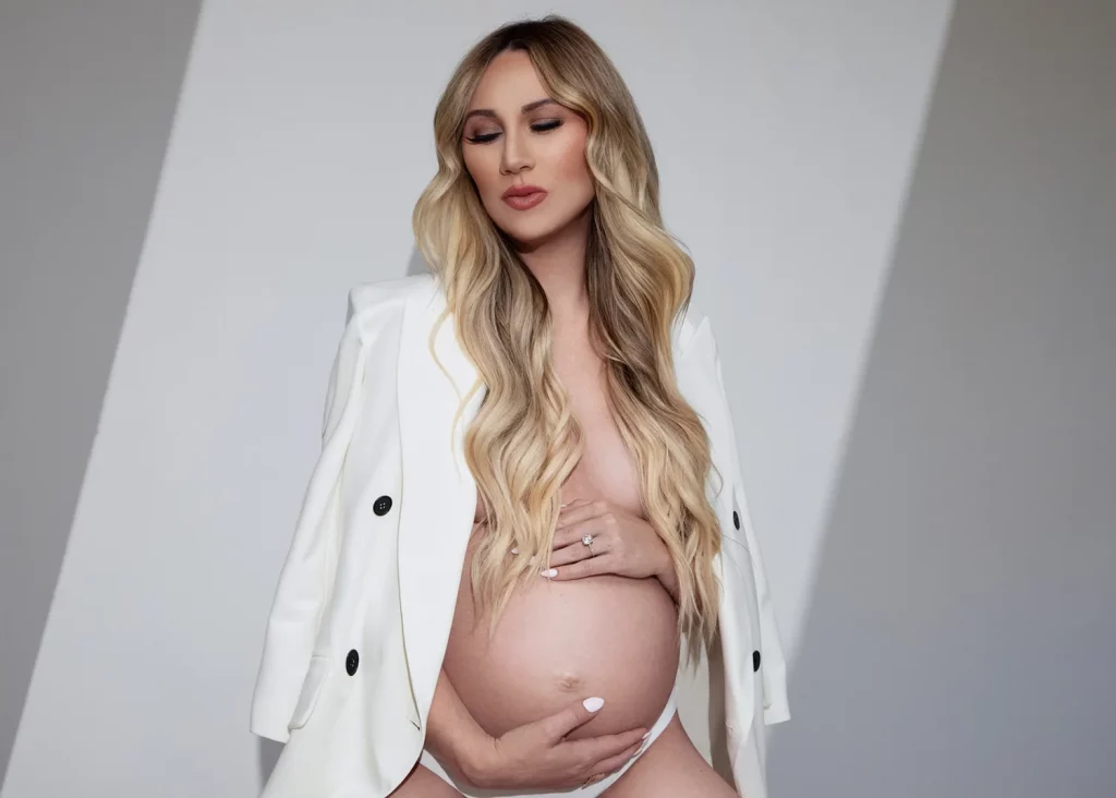 Maternity Boudoir Photograph of a pregnant woman in a white suit jacket and bra.